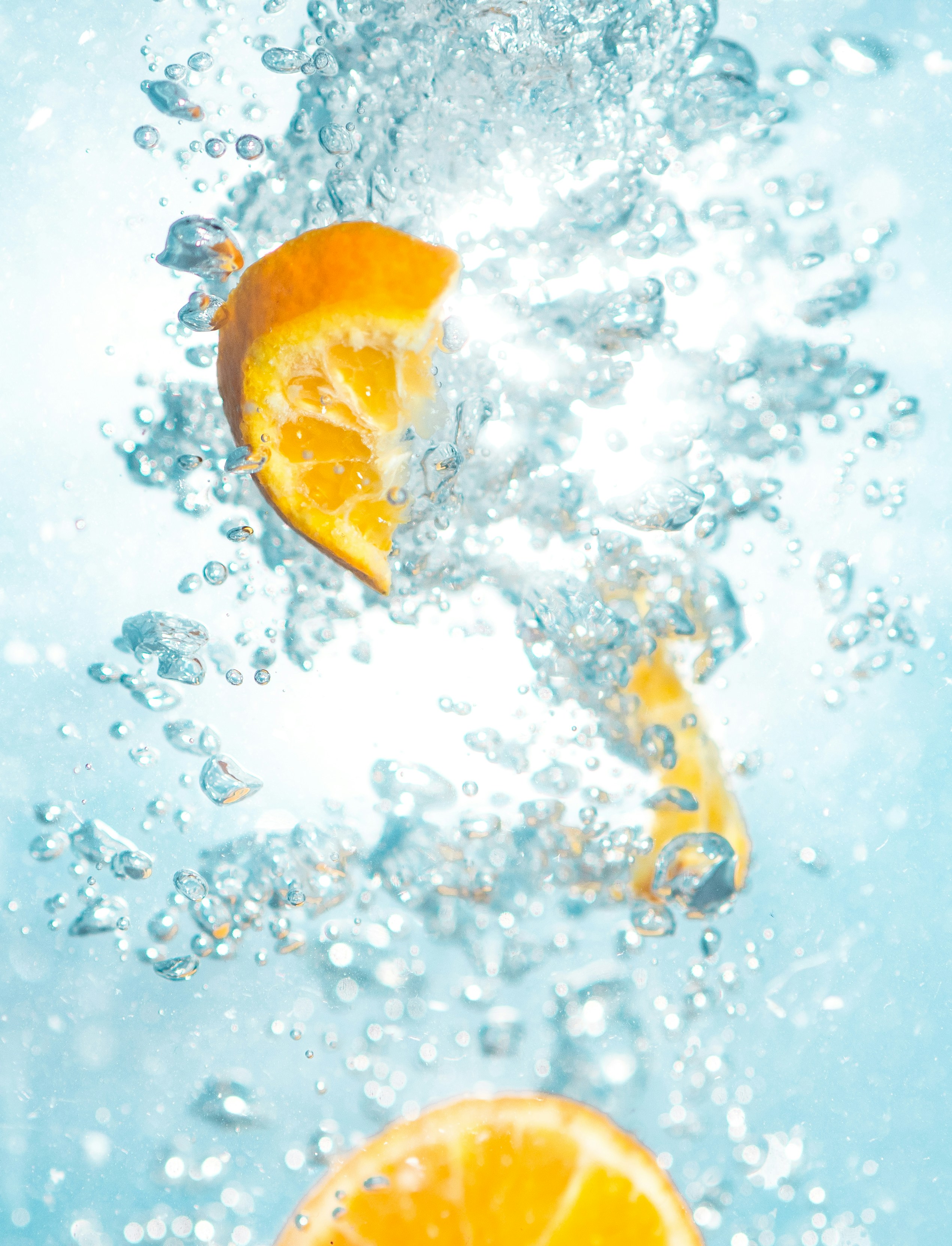 Photograph of a sliced orange fruit underwated. To be associated with freshness and summer. 