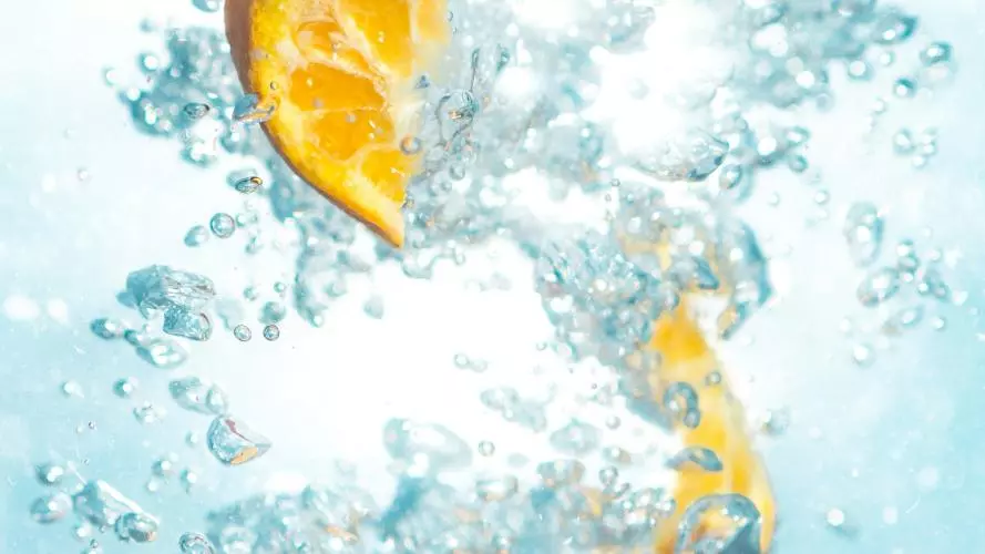 Photograph of a sliced orange fruit underwated. To be associated with freshness and summer. 