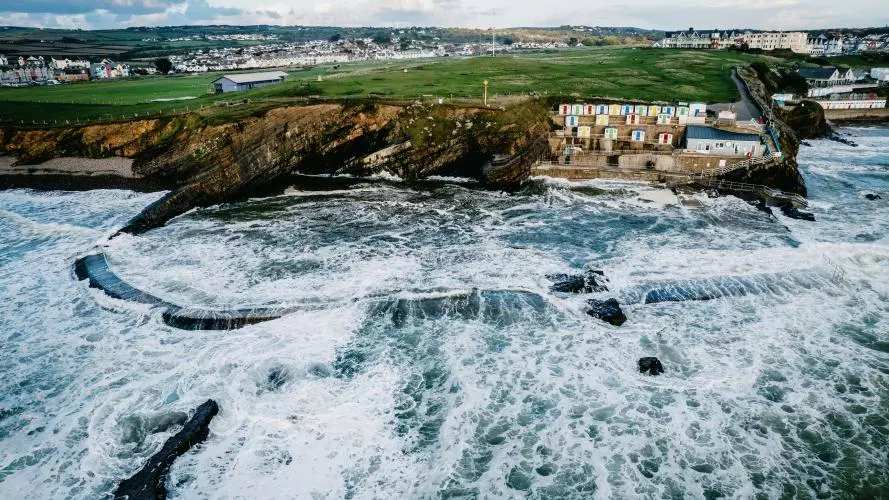 Cliffed coast with bathing cabins seen from the sea on a windy day.
