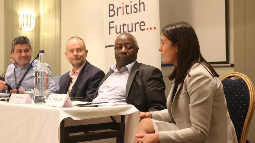 Photograph of discussing in one of British Future's events, in front of the organisation's logo. The panelists are of different genders and ethnic groups