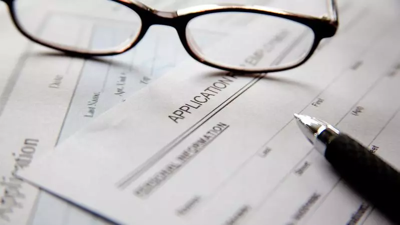 A pair of glasses abd a pen on empty application forms