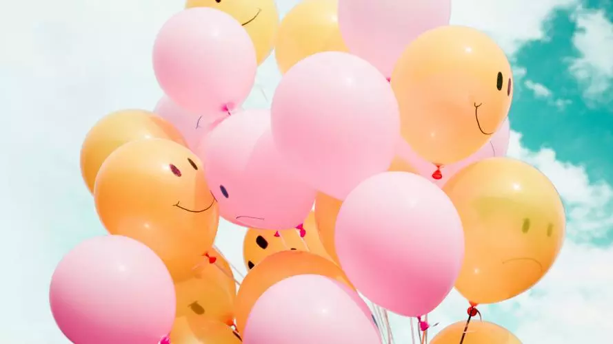 low angle photo of pink and yellow ballons with sketches of facial expressions on them