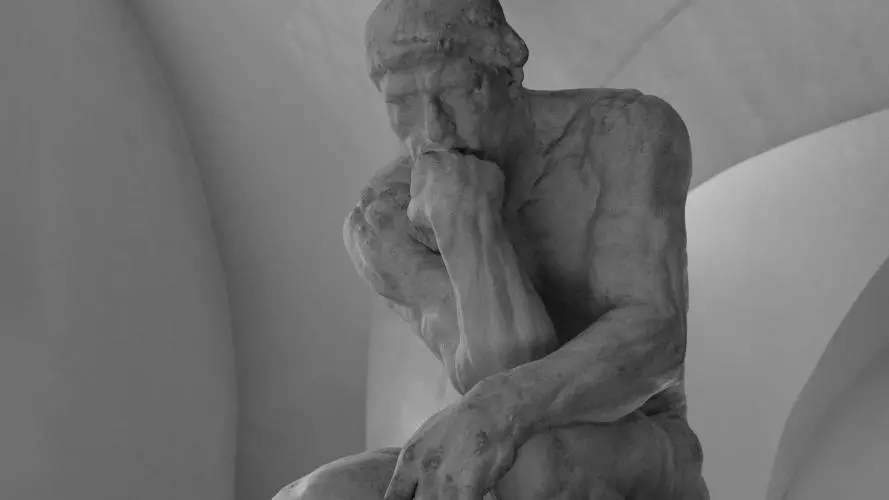 black and white photo of a statue of a man thinking
