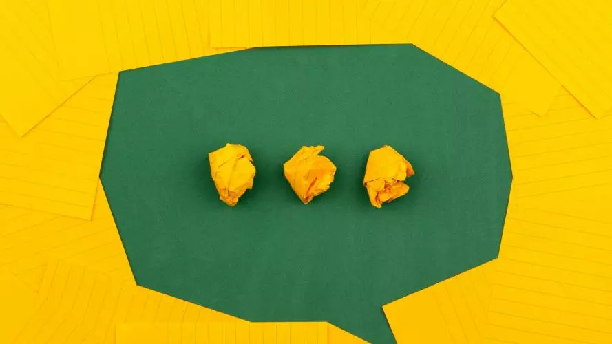 three crumpled yellow papers on green surface surrounded by yellow lined papers