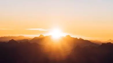 Picture of the sun rising between two mountain tops
