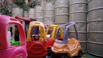 Photo of childrens' ride on toys in front of a barrier made of military barrels.