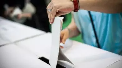 Hand of a person casting a ballot at a polling station during voting