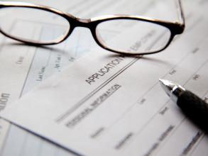 A pair of glasses abd a pen on empty application forms