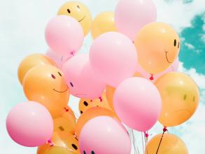 low angle photo of pink and yellow ballons with sketches of facial expressions on them
