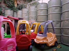 Photo of childrens' ride on toys in front of a barrier made of military barrels.