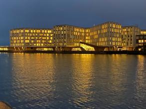 Evening photo of the WHO headquarters taken from across a body of water
