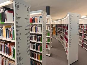 Photograph of interior space of the library, featuring white curved bookcases 