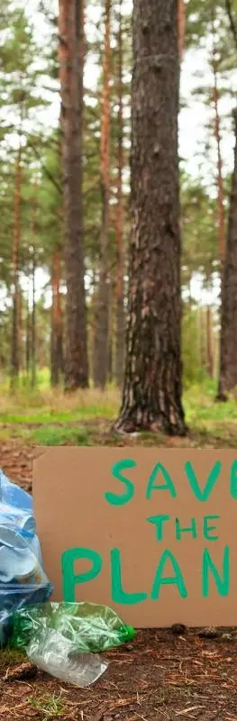 A small rubbish bag next to a "save the planet" sign in the woods
