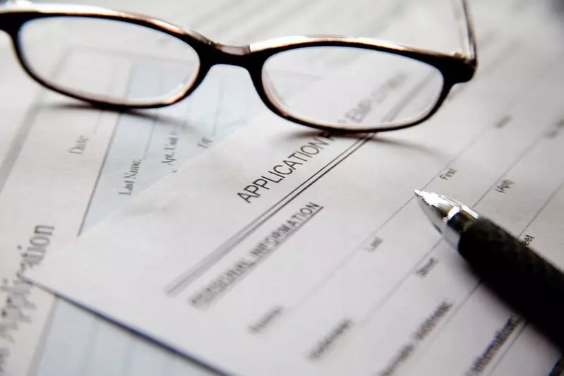 A pair of glasses abd a pen on empty application forms