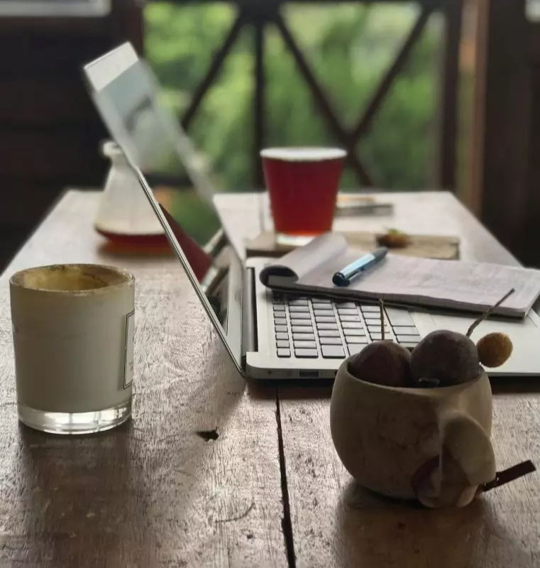 table with laptop, notepad, pen and cup of tea.